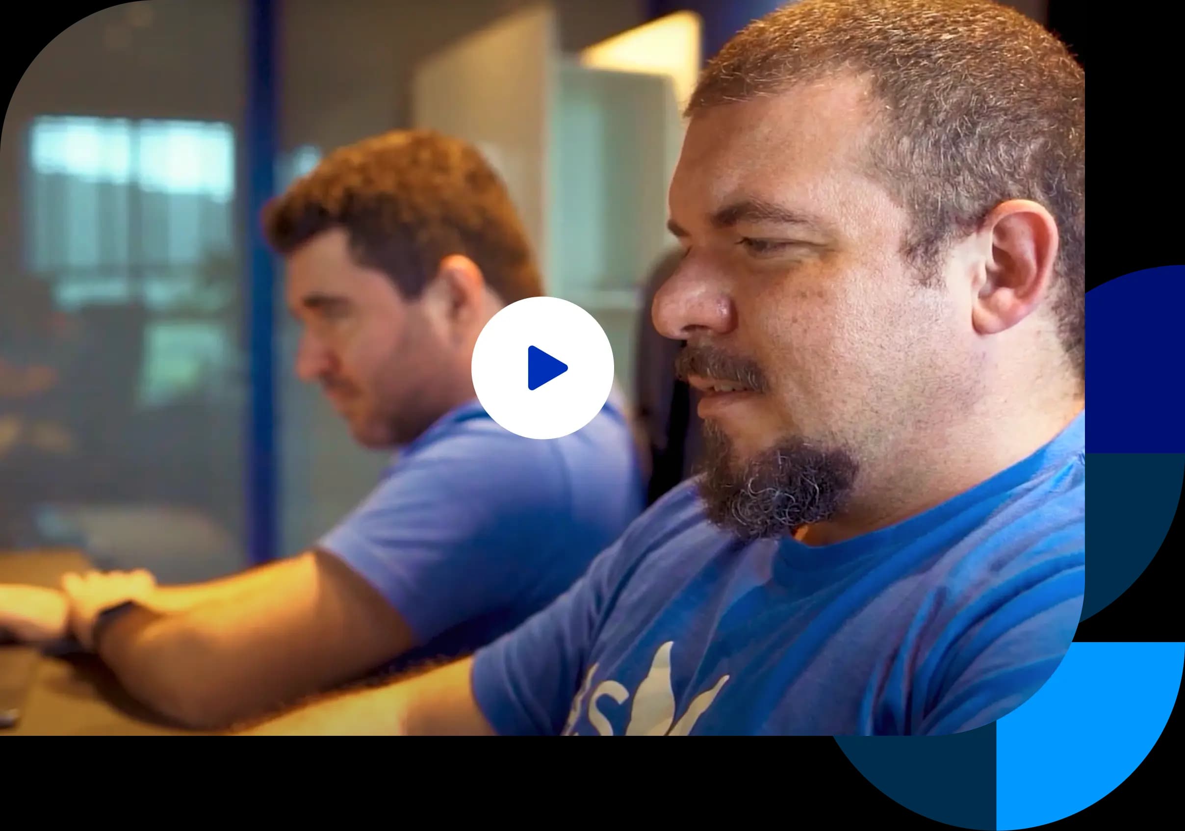 Os fundadores do Asaas, Piero Contezini e Diego Contezini, trabalham juntos no escritório. Diego aparece em primeiro plano e Piero aparece ao fundo, em desfoque. Ambos usam a camiseta azul com o logotipo do Asaas.