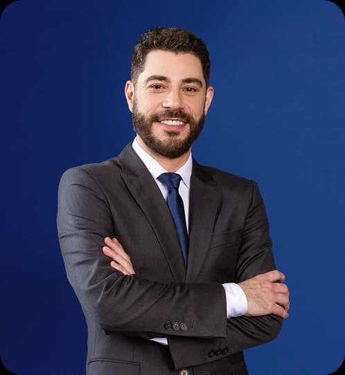 Evaristo Costa veste um terno e está de braços cruzados e sorrindo.